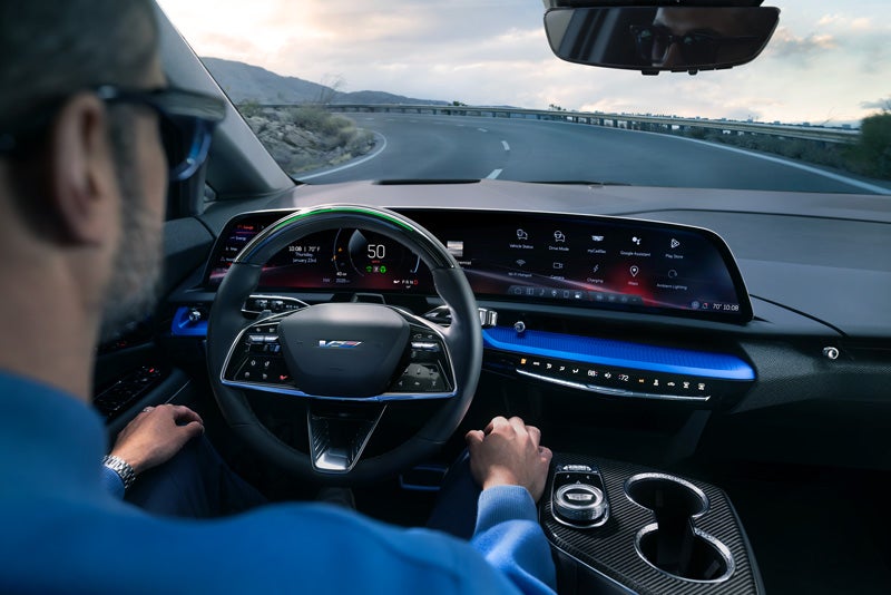 Front View of the 2026 OPTIQ-V Driving Through the Dusk Utilizing its Headlights | AutoNation Cadillac West Amarillo in AMARILLO TX