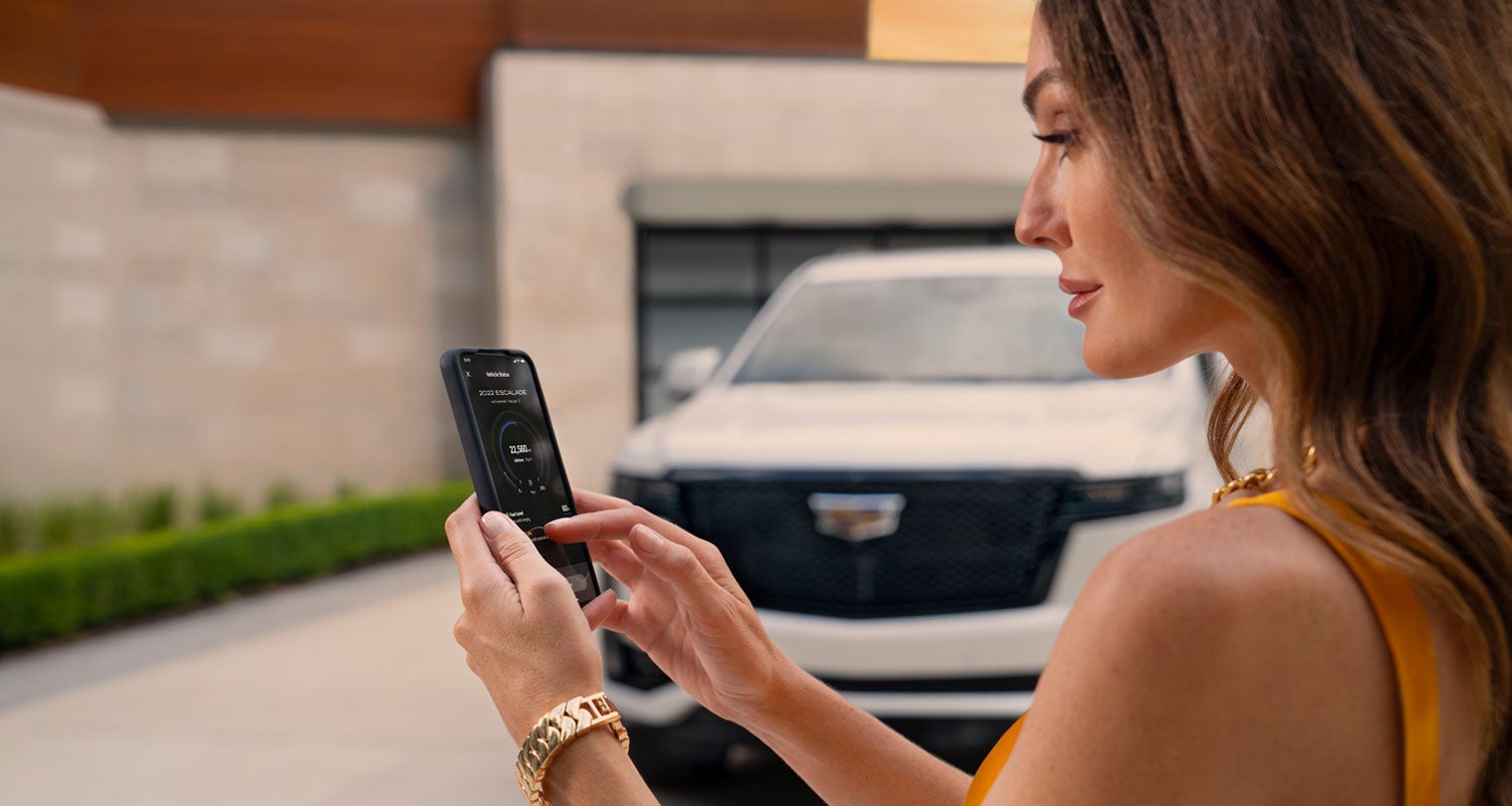 lady checking her mobile with a Cadillac vehicle background | AutoNation Cadillac West Amarillo in AMARILLO TX